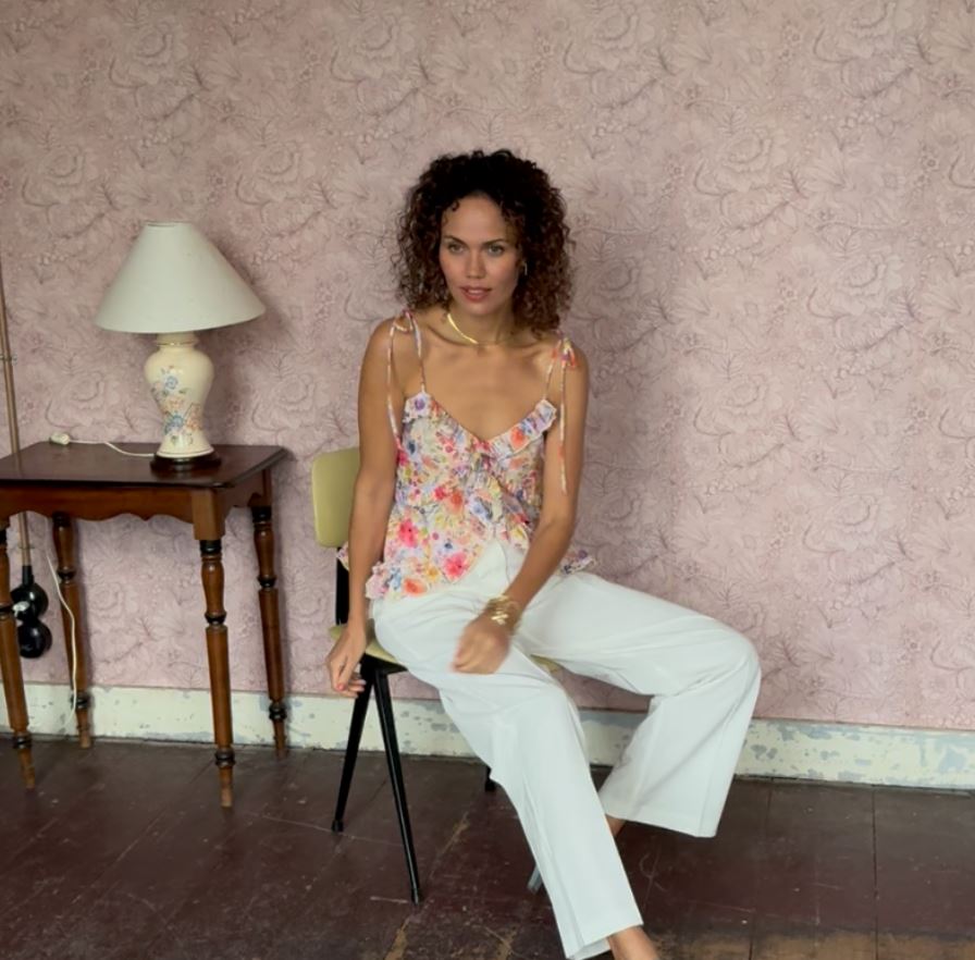 Fashion styling - Woman in styled floral top and white pants in elegant interior setting
